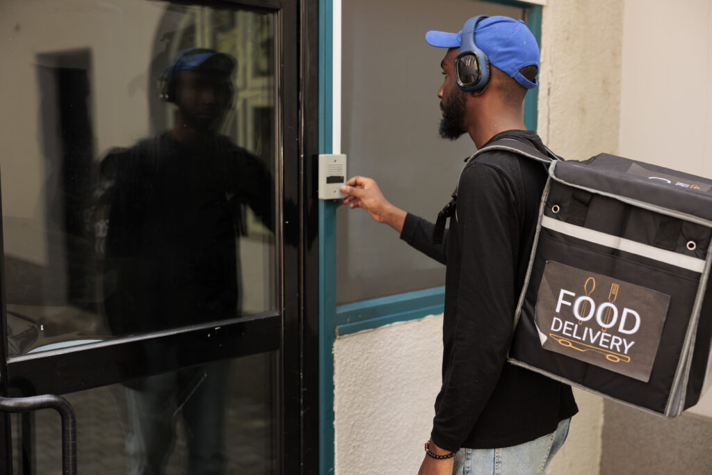 The Exciting Rise of Food Delivery Apps and their Impacts on Nigerian Eating Habits 13 business lunch delivery service courier ringing office building doorbell waiting client outdoors young african american man with backpack delivering takeaway restaurant meal