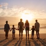 Family of four walking along a sunny beach, holding hands and enjoying quality time together during a fun seaside vacation.