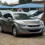 Affordable silver compact sedan parked in a used car dealership, representing budget-friendly cars for first-time drivers in Nigeria.