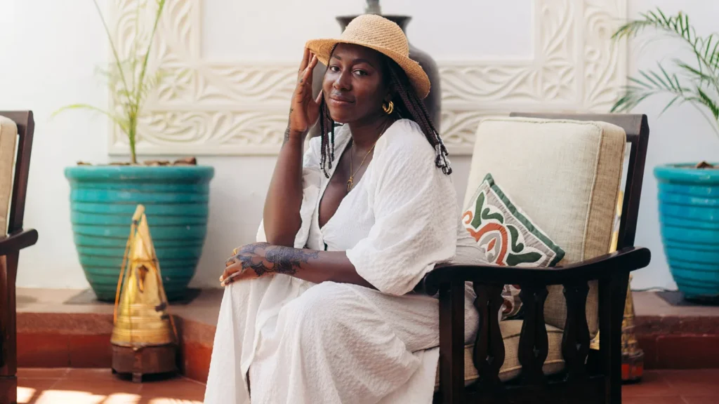 Solo female traveler wearing a white dress and straw hat, relaxing at a boutique hotel in Zanzibar during a safe and stylish solo vacation.