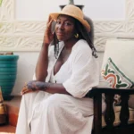 Solo female traveler wearing a white dress and straw hat, relaxing at a boutique hotel in Zanzibar during a safe and stylish solo vacation.
