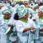 Guests dressed in coordinated white and green aso ebi outfits celebrating and dancing at a vibrant Nigerian owambe party.