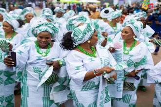 Guests dressed in coordinated white and green aso ebi outfits celebrating and dancing at a vibrant Nigerian owambe party.