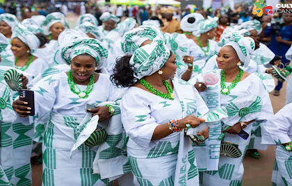 Guests dressed in coordinated white and green aso ebi outfits celebrating and dancing at a vibrant Nigerian owambe party.