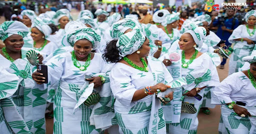 Guests dressed in coordinated white and green aso ebi outfits celebrating and dancing at a vibrant Nigerian owambe party.
