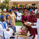 Yoruba traditional wedding ceremony with couple in blue and gold attire receiving family gifts and dowry items"