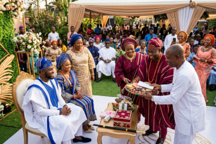 Yoruba traditional wedding ceremony with couple in blue and gold attire receiving family gifts and dowry items"
