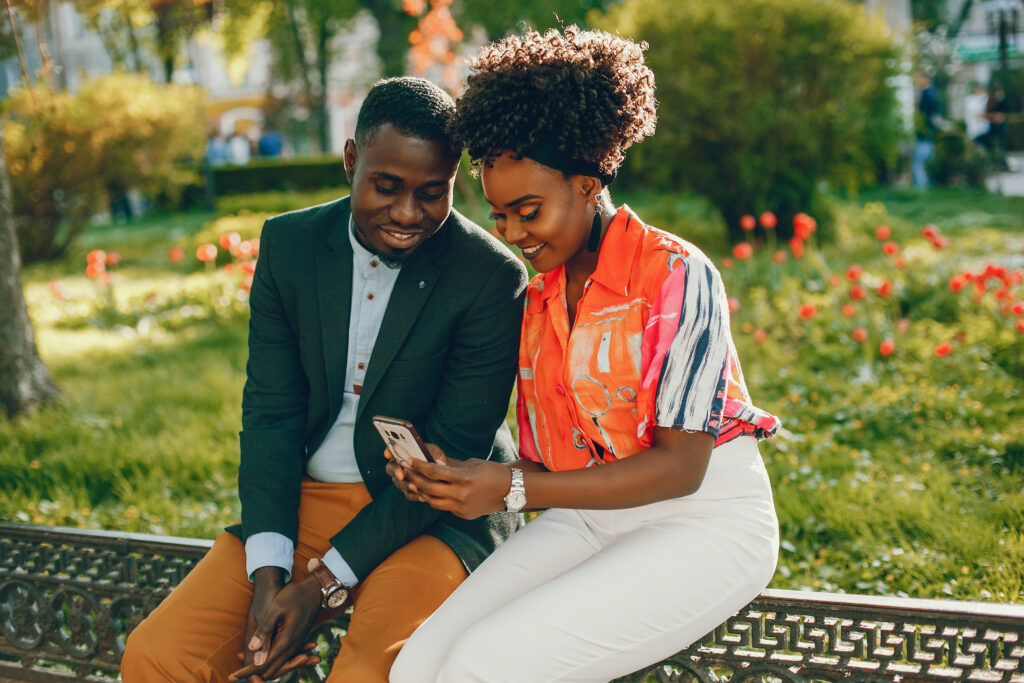 Why your girlfriend might be finding your messages boring (Tips to compose a heart-melting message) 2 young stylish dark skinned couple sitting sunny city use phone